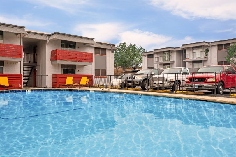 a pool with cars parked in front of it at The Cantera Apartment Homes