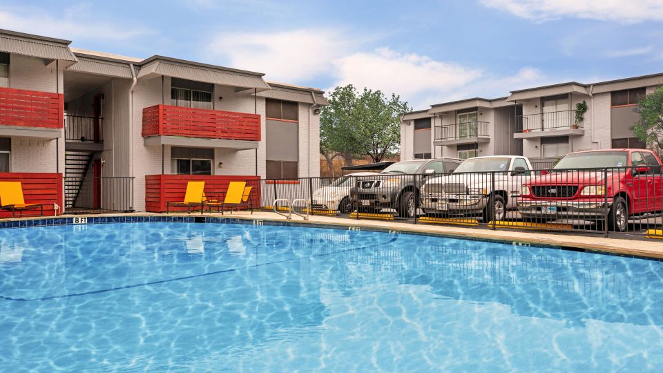 a pool with cars parked in front of it at The Cantera Apartment Homes