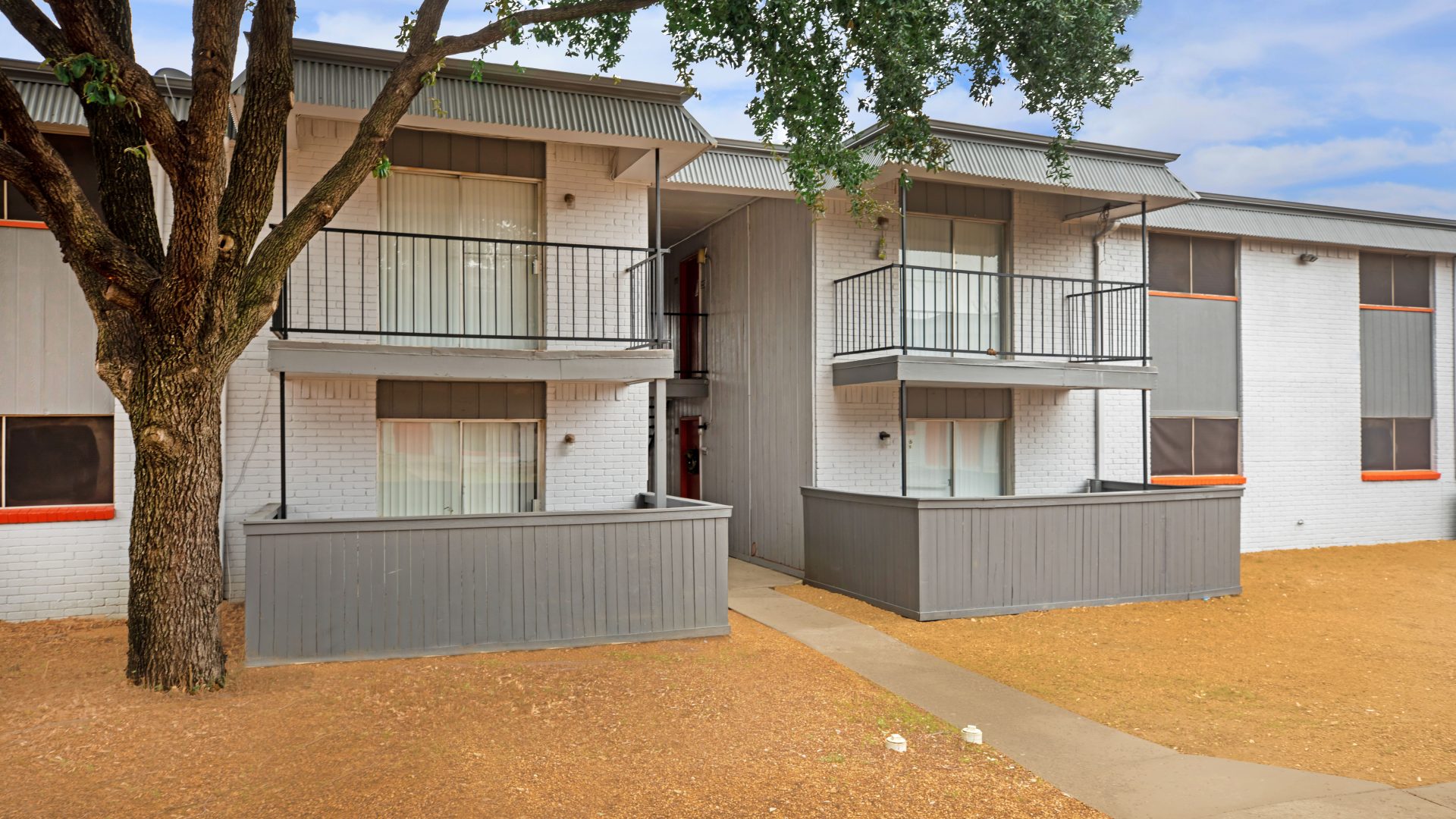 the apartment complex has two balconies and a tree at The Cantera Apartment Homes